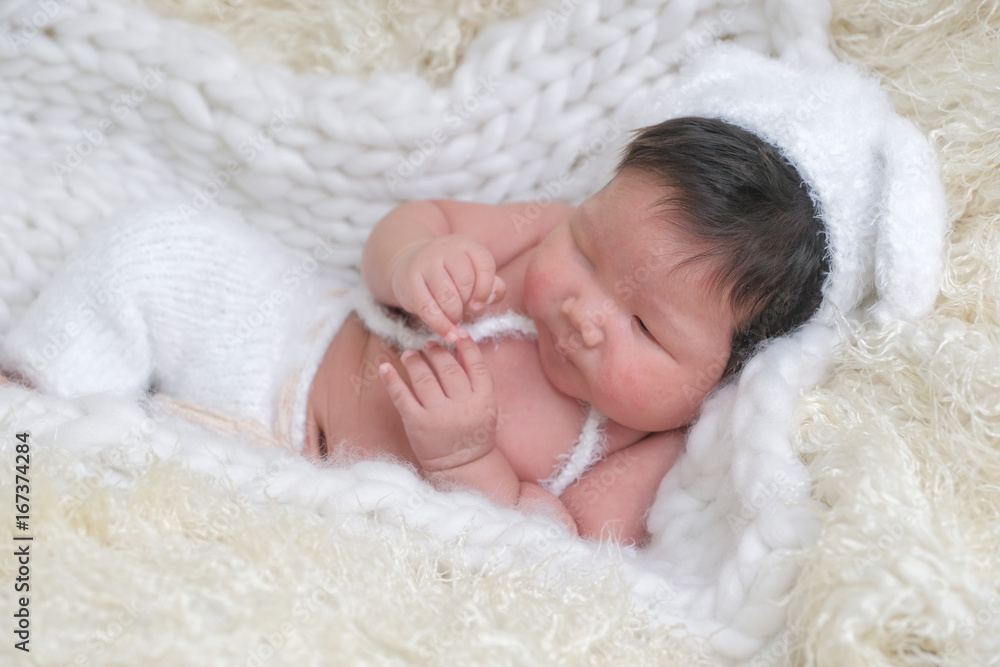 cute asian boy newborn portrait with white doll one month lie down on white background fur . cute asian boy newborn portrait with white doll one month lie down on white background fur .