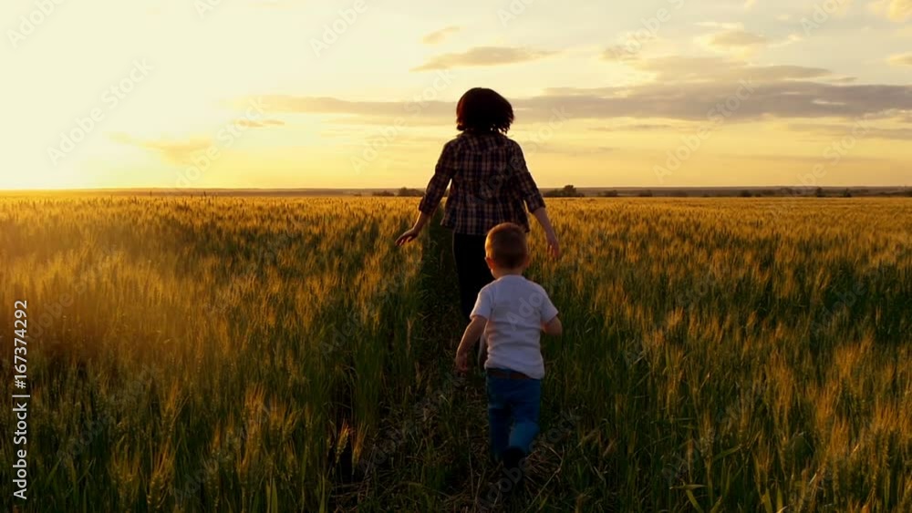 Mom and baby running across the wheat field toward the sunset. Mom and baby running across the wheat field toward the sunset.