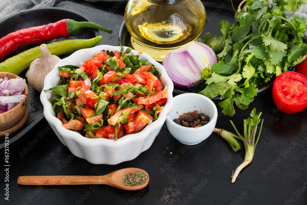 Traditional mexican salsa sauce and ingredients on black table.