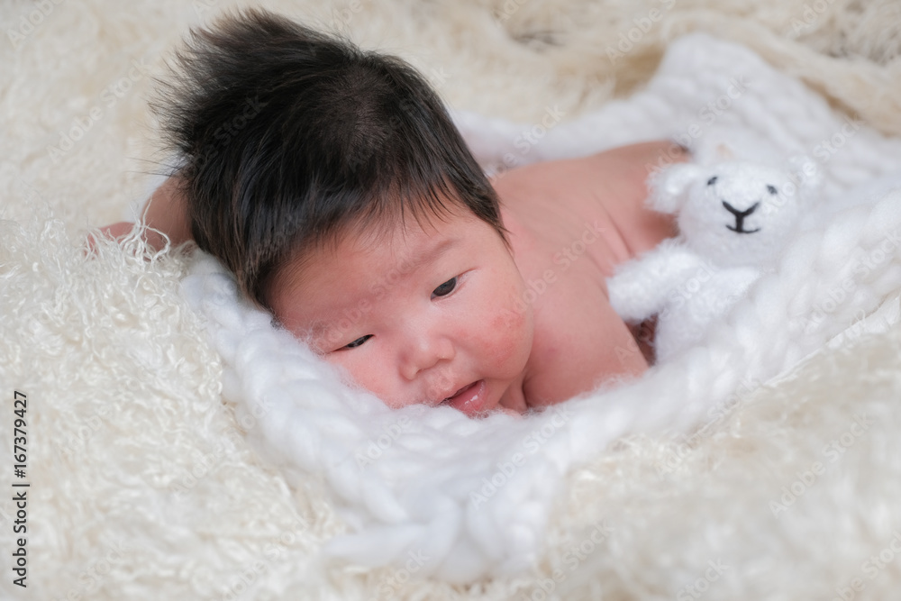 cute asian boy newborn portrait with white doll one month lie down on white background fur . cute asian boy newborn portrait with white doll one month lie down on white background fur .