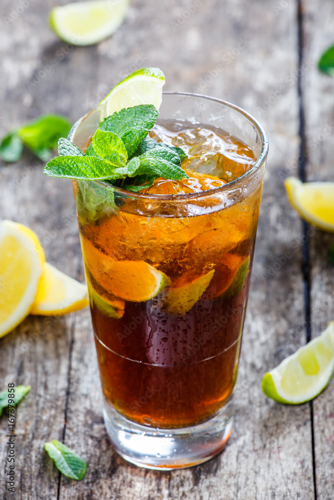 Cold cola with mint, lime and ice in glass on wooden background. Summer drinks and alcoholic cocktails. Cold cola with mint, lime and ice in glass on wooden background. Summer drinks and alcoholic cocktails.