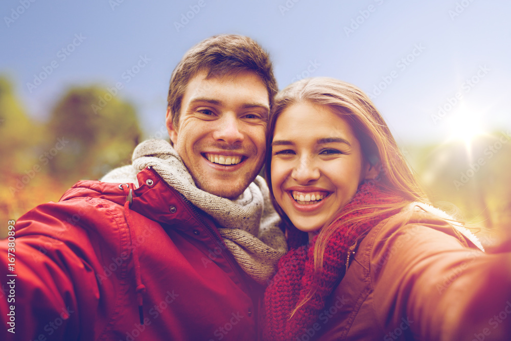 happy young couple taking selfie in autumn park