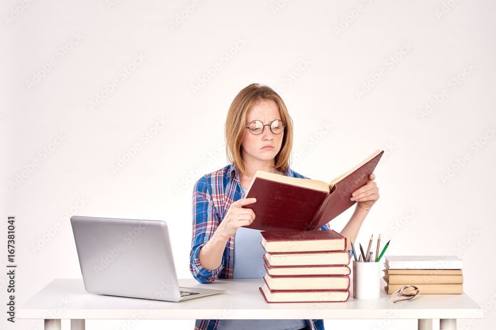 Beautiful teenage schoolgirl sitting at desk with stack of books on it Beautiful teenage schoolgirl sitting at desk with stack of books on it