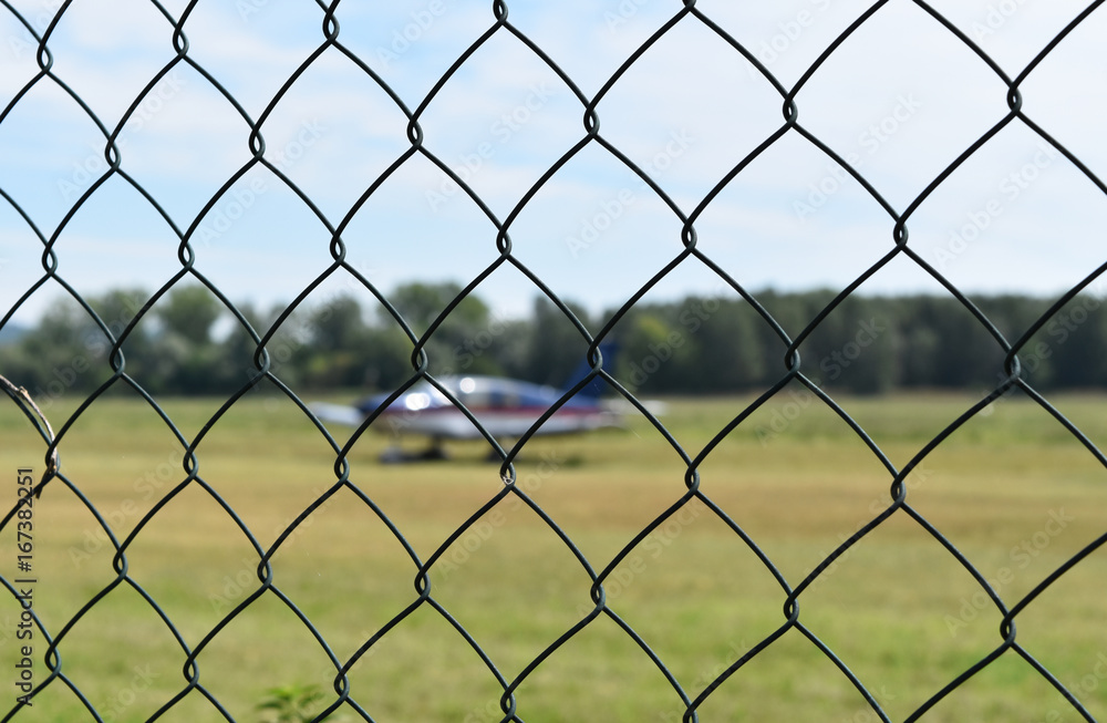 A net with a small airplane on a field behind A net with a small airplane on a field behind
