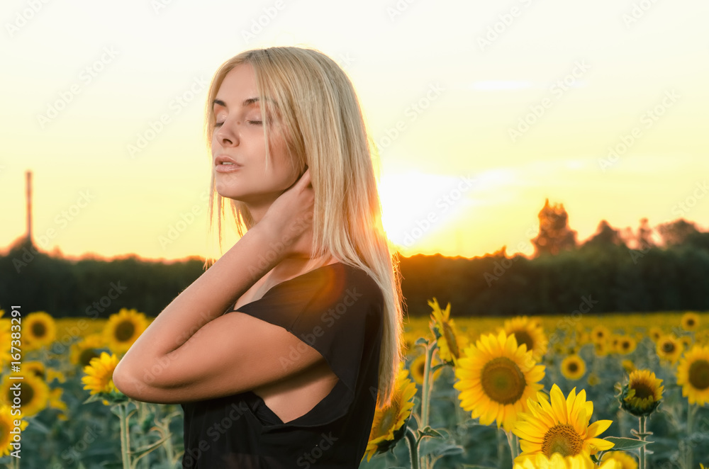 portrait beautiful young blonde model in black dress on a field of sunflowers portrait beautiful young blonde model in black dress on a field of sunflowers