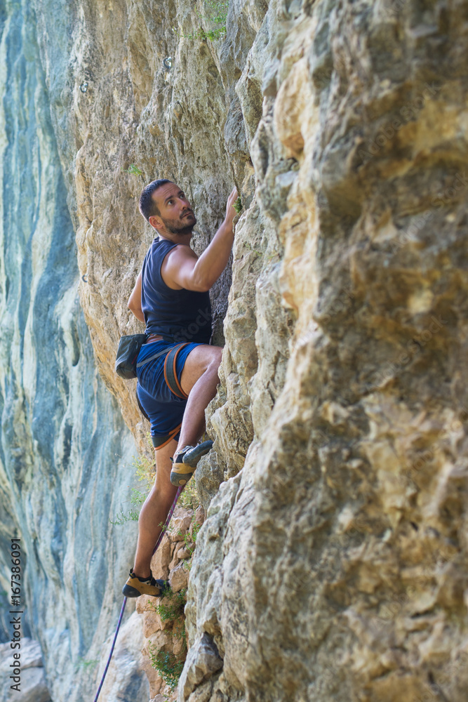 Rock climber with hand in chalk bag hanging on boulder