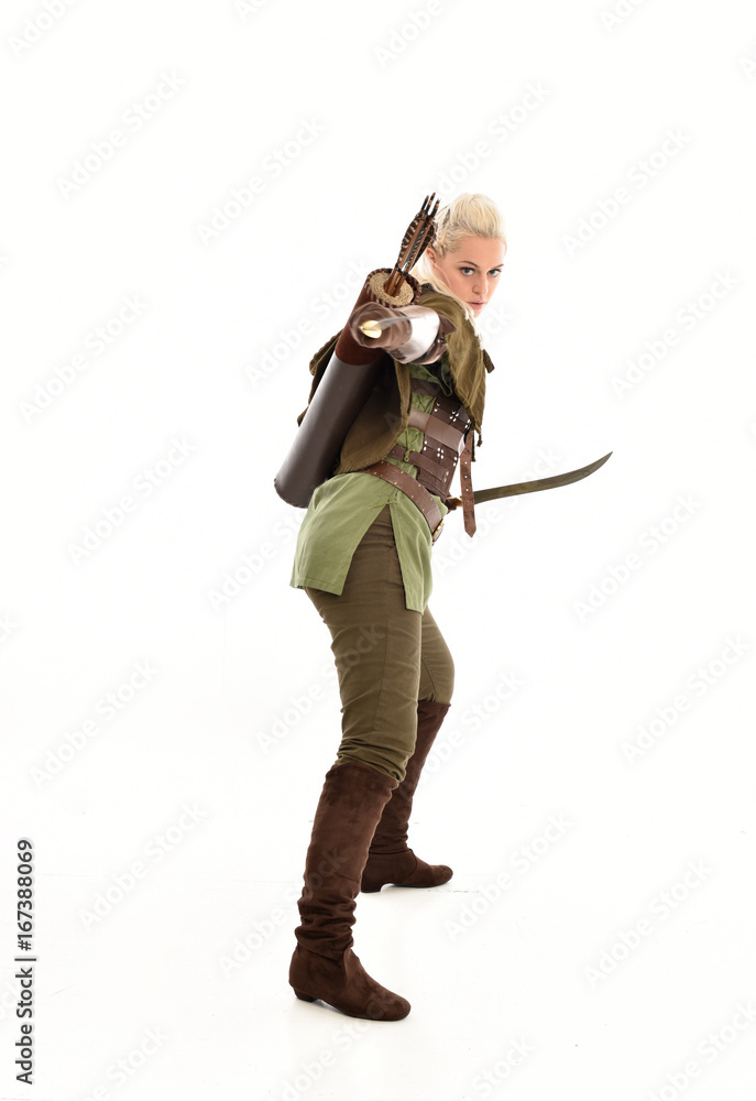 full length portrait of a blonde girl wearing green and brown medieval costume, holding a bow and arrow. isolated on white background. full length portrait of a blonde girl wearing green and brown medieval costume, holding a bow and arrow. isolated on white background.