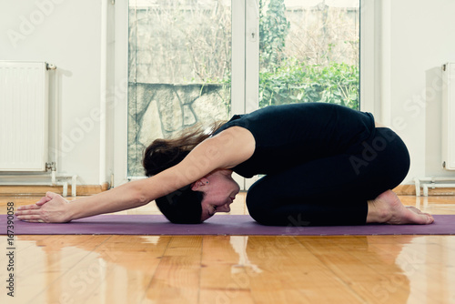Woman doing Yoga at home - Half Tortoise Position