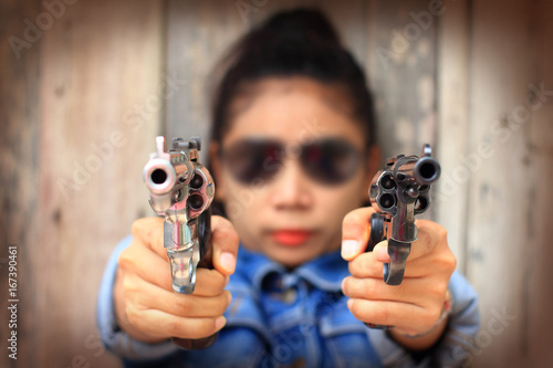 Fototapeta The woman in jeans suit at the shooting range shot from a revolvers