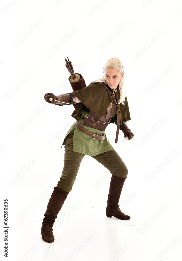 full length portrait of a blonde girl wearing green and brown medieval costume, holding a bow and arrow. isolated on white background. full length portrait of a blonde girl wearing green and brown medieval costume, holding a bow and arrow. isolated on white background.