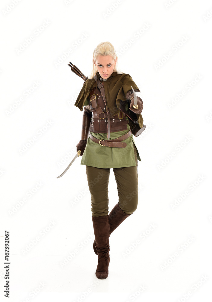 full length portrait of a blonde girl wearing green and brown medieval costume, holding a bow and arrow. isolated on white background.