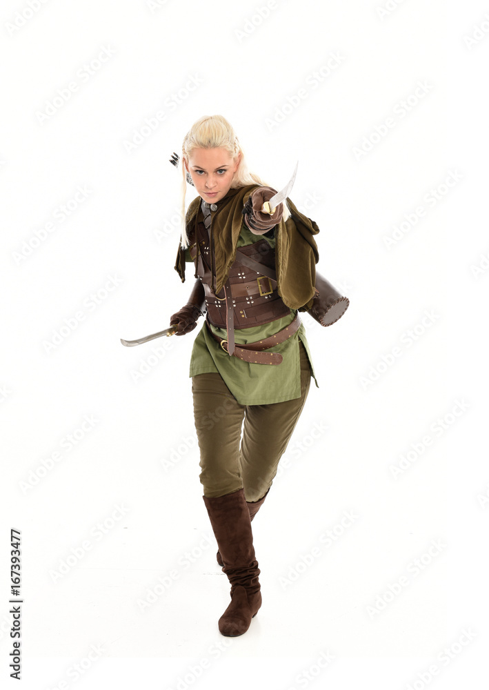 full length portrait of a blonde girl wearing green and brown medieval costume, holding a bow and arrow. isolated on white background. full length portrait of a blonde girl wearing green and brown medieval costume, holding a bow and arrow. isolated on white background.