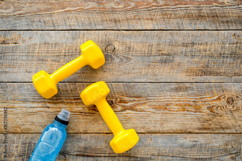 Fitness background. Dumbbells and water on wooden background top view copyspace
