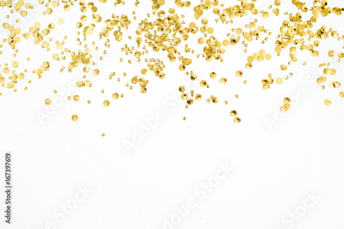 Golden confetti tinsel on white background. Flat lay, top view. Minimal background. photo