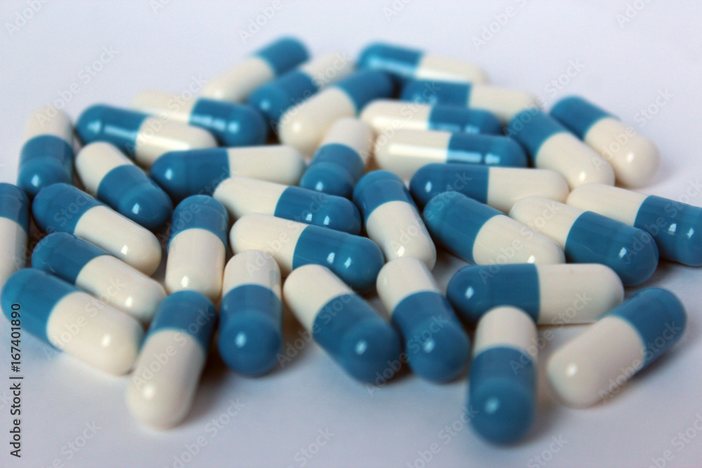 Pills scattered on a white background, medicine and treatment blue and blue