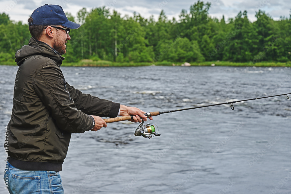 Man fishing with spinning rod in a rapid river. Man fishing with spinning rod in a rapid river.