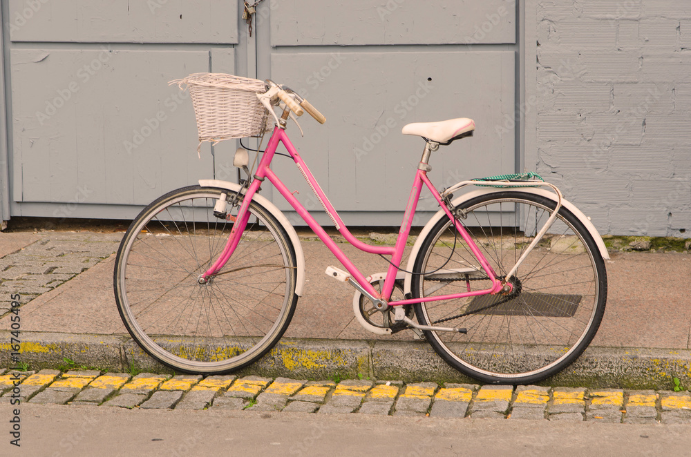 Old style pink bicycle parked on the street