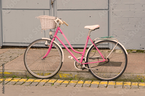Old style pink bicycle parked on the street