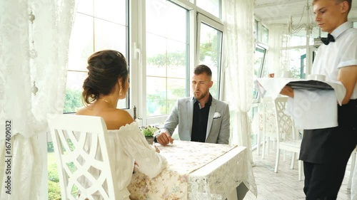 waiter brought cup of coffee for beautiful couple in a cafe photo