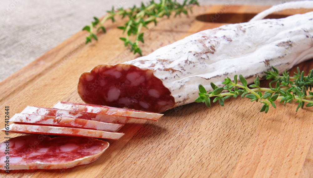 salami slicing with thyme on board salami slicing with thyme on board
