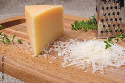 grated parmesan cheese and metal grater on wooden plate