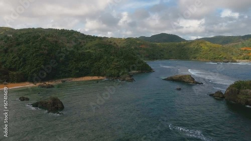 The coast of the tropical island with the mountains and the rainforest on a background of ocean with big waves.Aerial view: sea and the tropical island with rocks, beach and waves. Seascape: sky photo