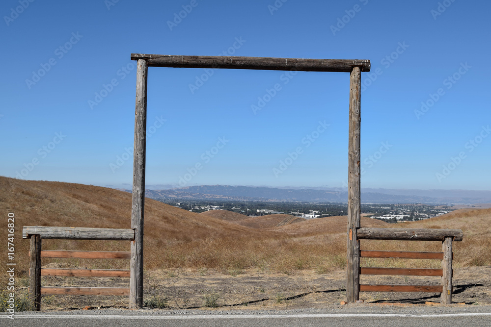 Old Wooden Framed Entrance to Farmland, with a blue sky and mountain range in the distance