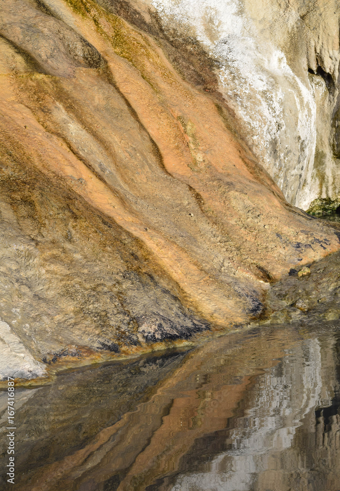 Reflection of natural rock, dyed with mineral, in a  hot spring pool