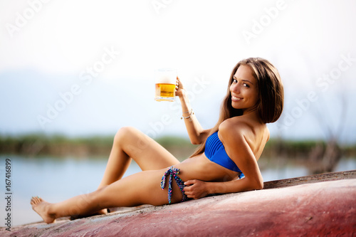 girl with beer mug on an upside down rowboat photo