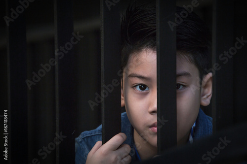 asian boy Hand in jail looking out the window
