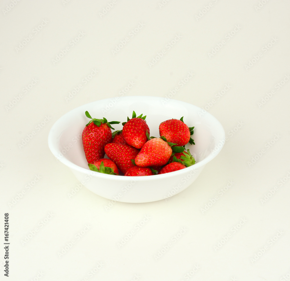 Fresh strawberries with leaf in a white bowl on white background Fresh strawberries with leaf in a white bowl on white background