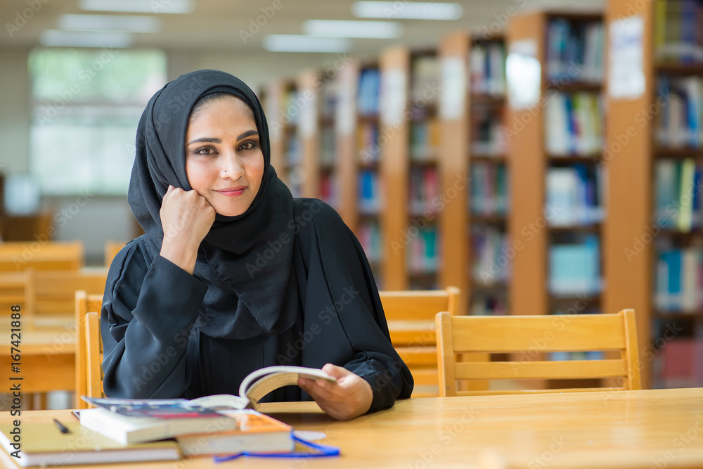 Muslim woman reading book at the library. Muslim woman reading book at the library.