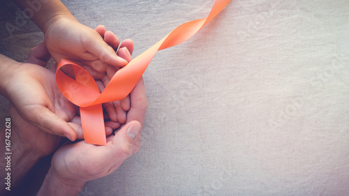 Adult and child hands holding orange Ribbons, Leukemia cancer awareness and Multiple sclerosis awareness, COPD,ADHD awareness, world kidney day