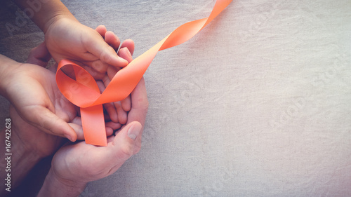 Adult and child hands holding orange Ribbons, Leukemia cancer awareness and Multiple sclerosis awareness, COPD,ADHD awareness, world kidney day photo