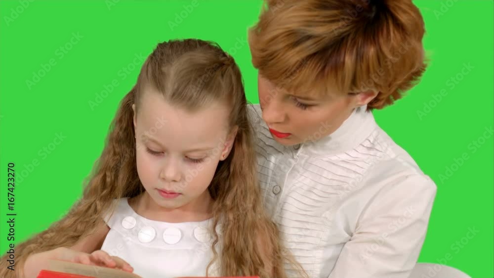 Mother and daughter reading a book with enthusiasm on a Green Screen, Chroma Key Mother and daughter reading a book with enthusiasm on a Green Screen, Chroma Key