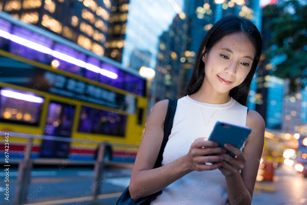 Fototapeta premium Woman using cellphone in Hong Kong city at night