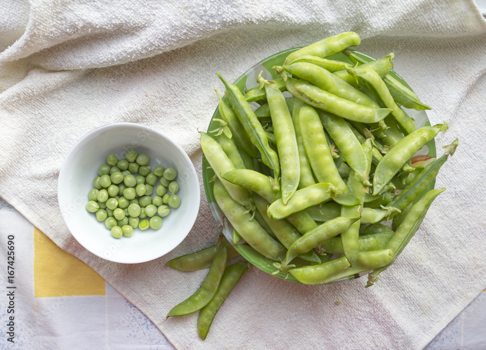 Green peas. Pile of pods in a glass bowl. Vegetables, vegetarianism