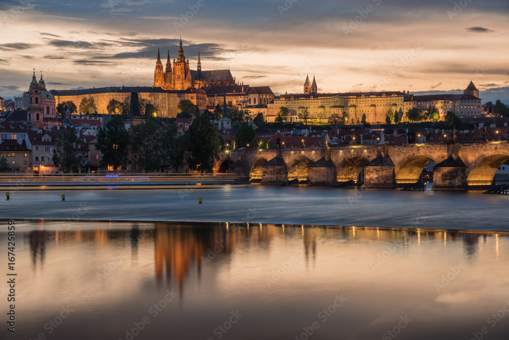 Prague Castle with cloudy sunset and Charles Bridge light up