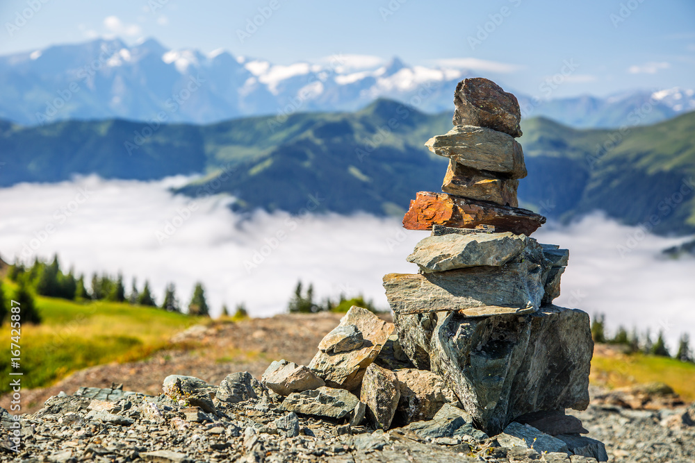 Naklejka premium Pyramid made by stones and austrian alps in the background. Photo taken on Asitz moutain in Leogang Salzburg