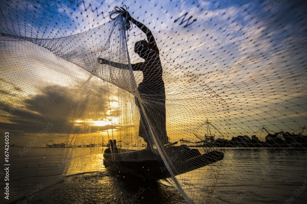 silhouette of fisherman with sunrise and big fish net in the background  Stock Photo