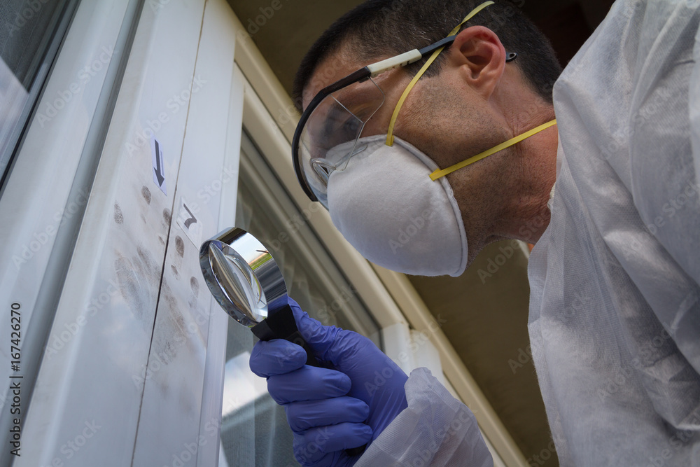 Male forensic expert find fingerprints on the window with help of a