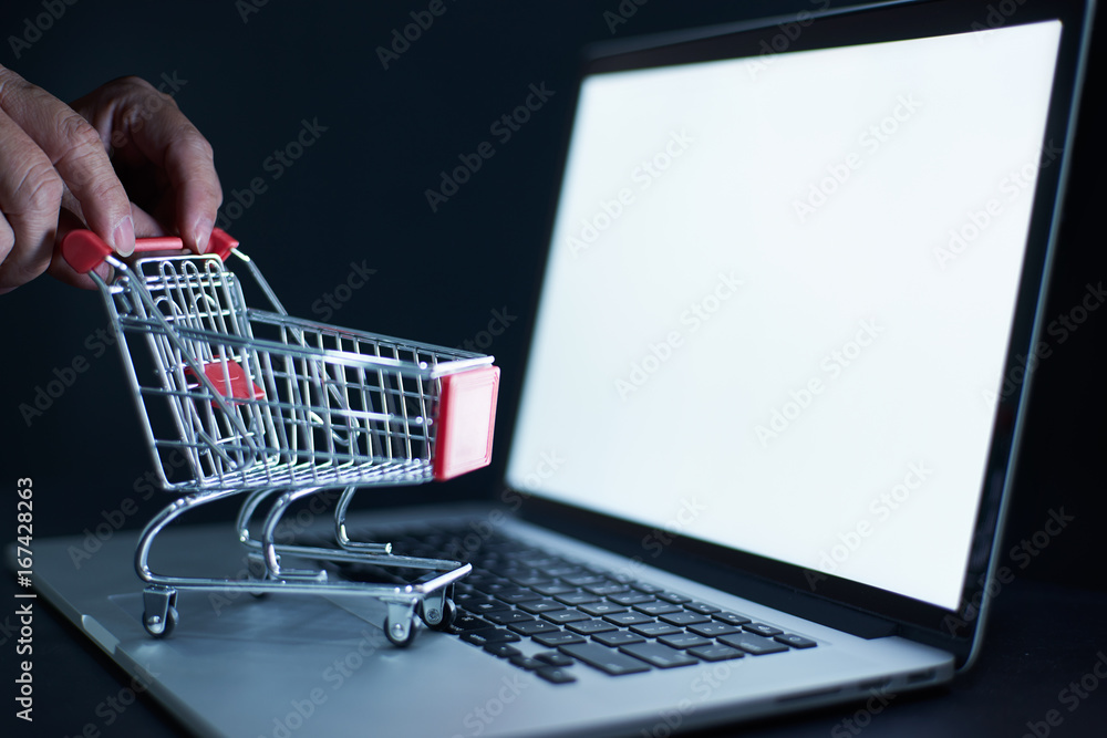 Shopping cart or trolley in front of Laptop , online marketing and business trading concept. Shopping cart or trolley in front of Laptop , online marketing and business trading concept.