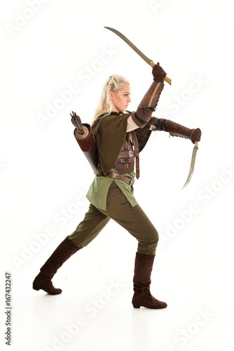  full length portrait of a blonde girl wearing green and brown medieval costume. standing pose isolated on white background.