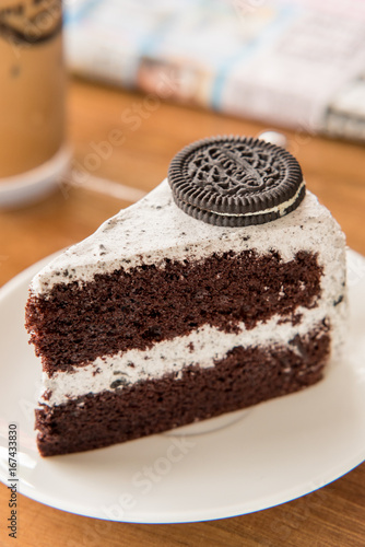 Chocolate Cake with oreo and whipped cream on white plate and wood table has ready to served.