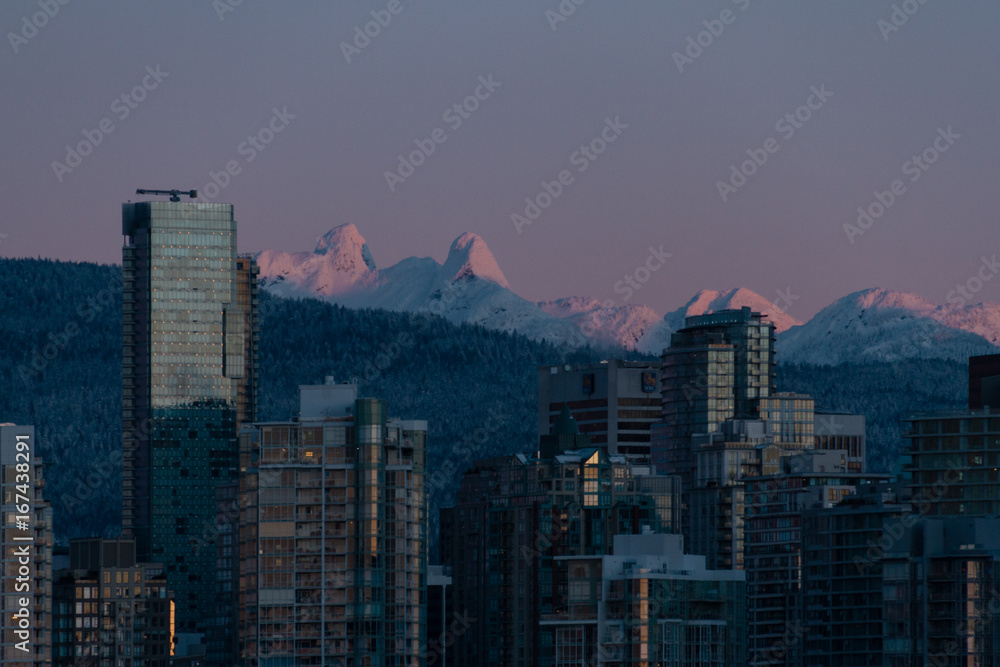 Winter cityscape with mountains and sunrise illuminating building