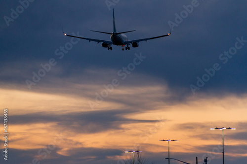 Plane flying low over parking lot while sunset © Martin Hossa