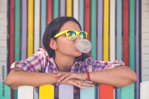 Young female leaning on fence and chewing gum