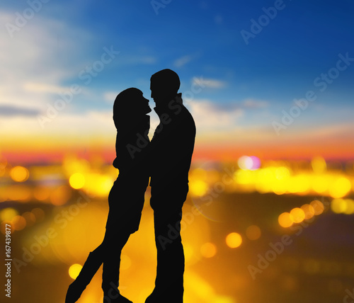 silhouette of romantic lovers with blurred city on a background