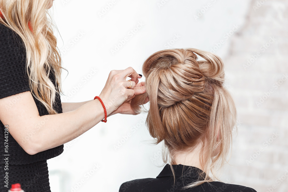 Fototapeta premium Beauty blond woman in hairdresser salon making an evening or wedding hair style