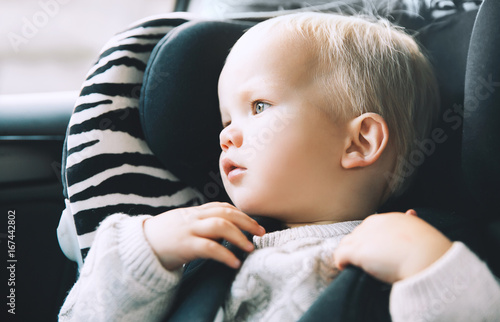 Portrait of toddler boy sitting in car seat. photo